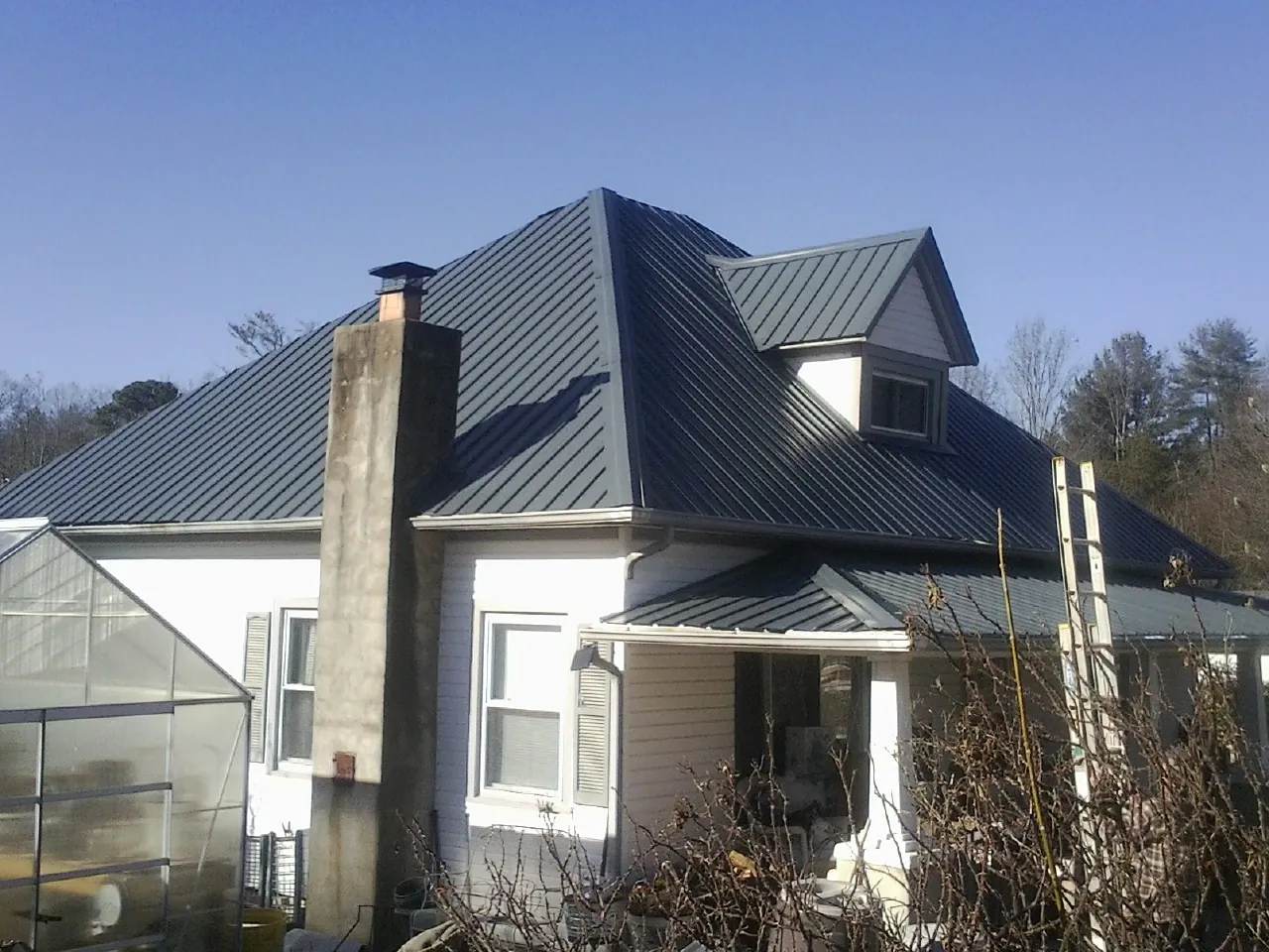 Dark blue standing seam metal roof on a white farmhouse with dormer — Slate & Tile Roof Repair by Roofing Brothers in Waldport