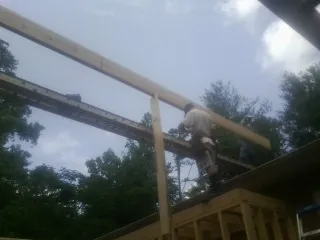 Carpenter setting a ridge beam over a new addition frame — Ice Dam Removal by Roofing Brothers in Waldport