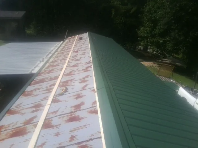 Old rusted panels beside newly installed green metal roofing — Wind Damage Roof Repair by Roofing Brothers in Waldport