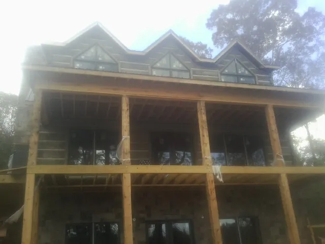 Dormers and porch framing on a large log home under construction — Roof Coating work by our crew in Waldport