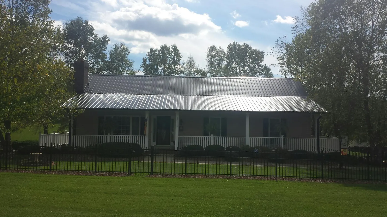 Gray metal roof on a brick ranch with a full width front porch — Gutter Guard Installation work by our crew in Waldport