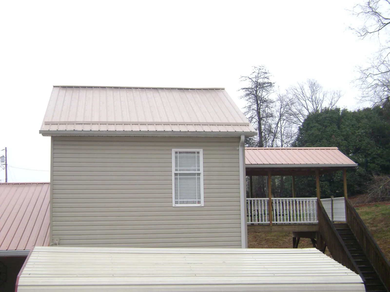Tan metal roofs on a two story addition and attached porch, from a Roof Replacement job in Waldport
