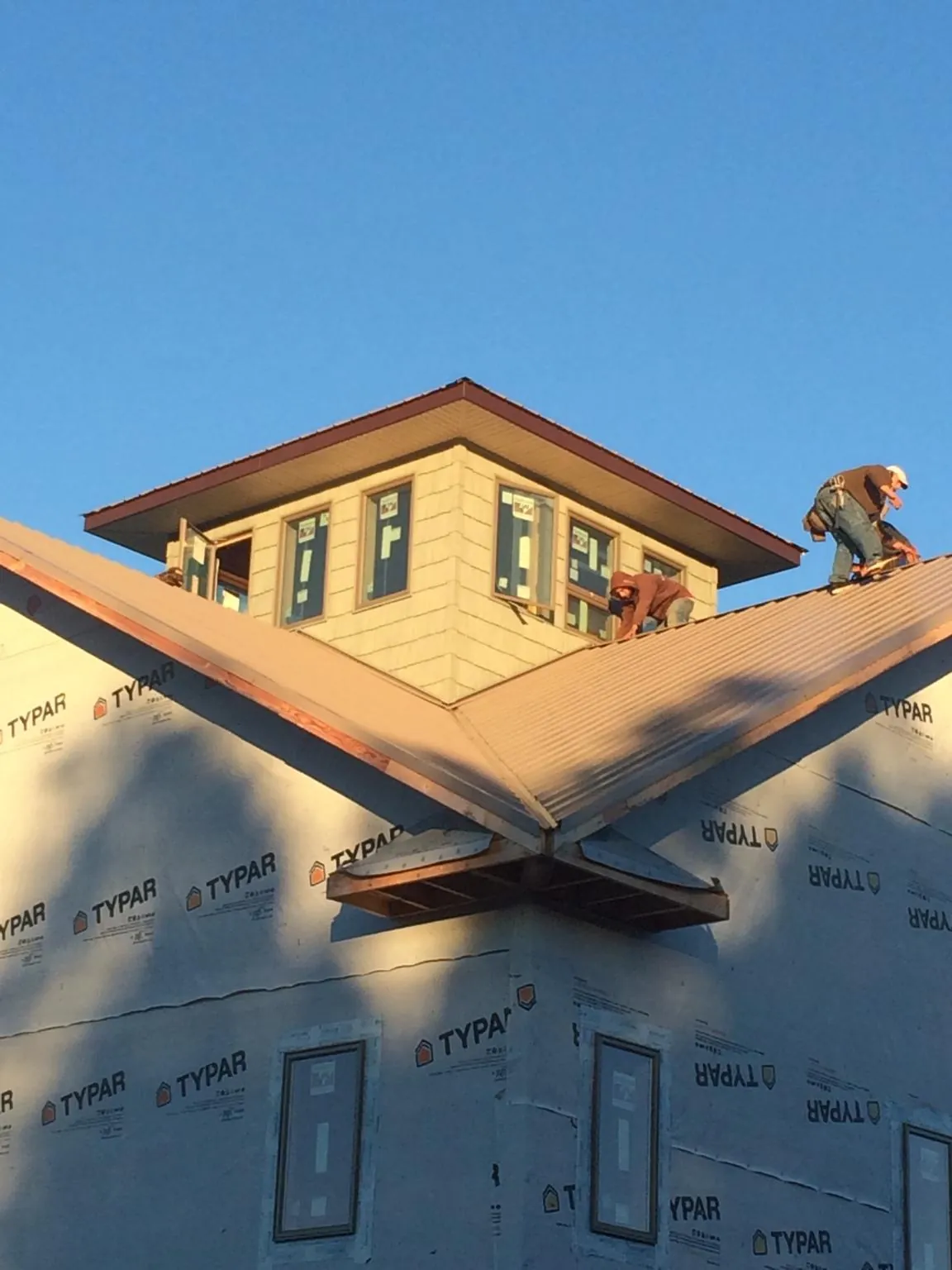 Roofers working around a rooftop cupola on a new metal roof at sunset — Roof Waterproofing in Waldport by Roofing Brothers
